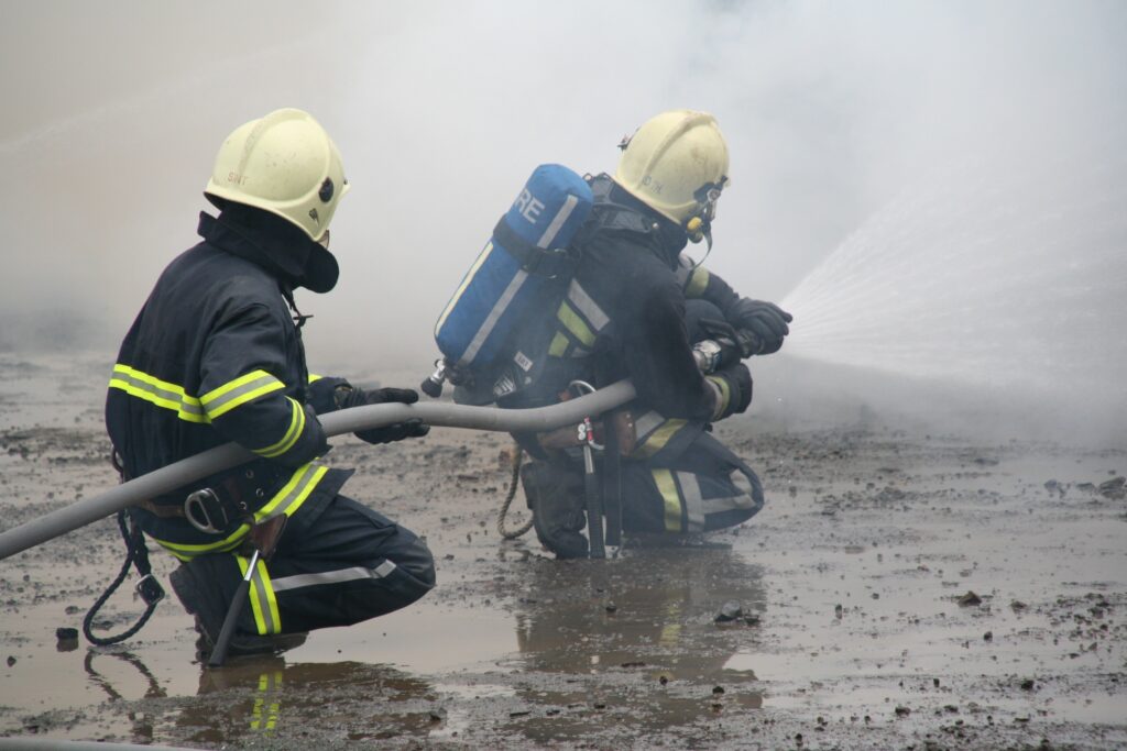 Deux pompiers utilisant une lance incendie